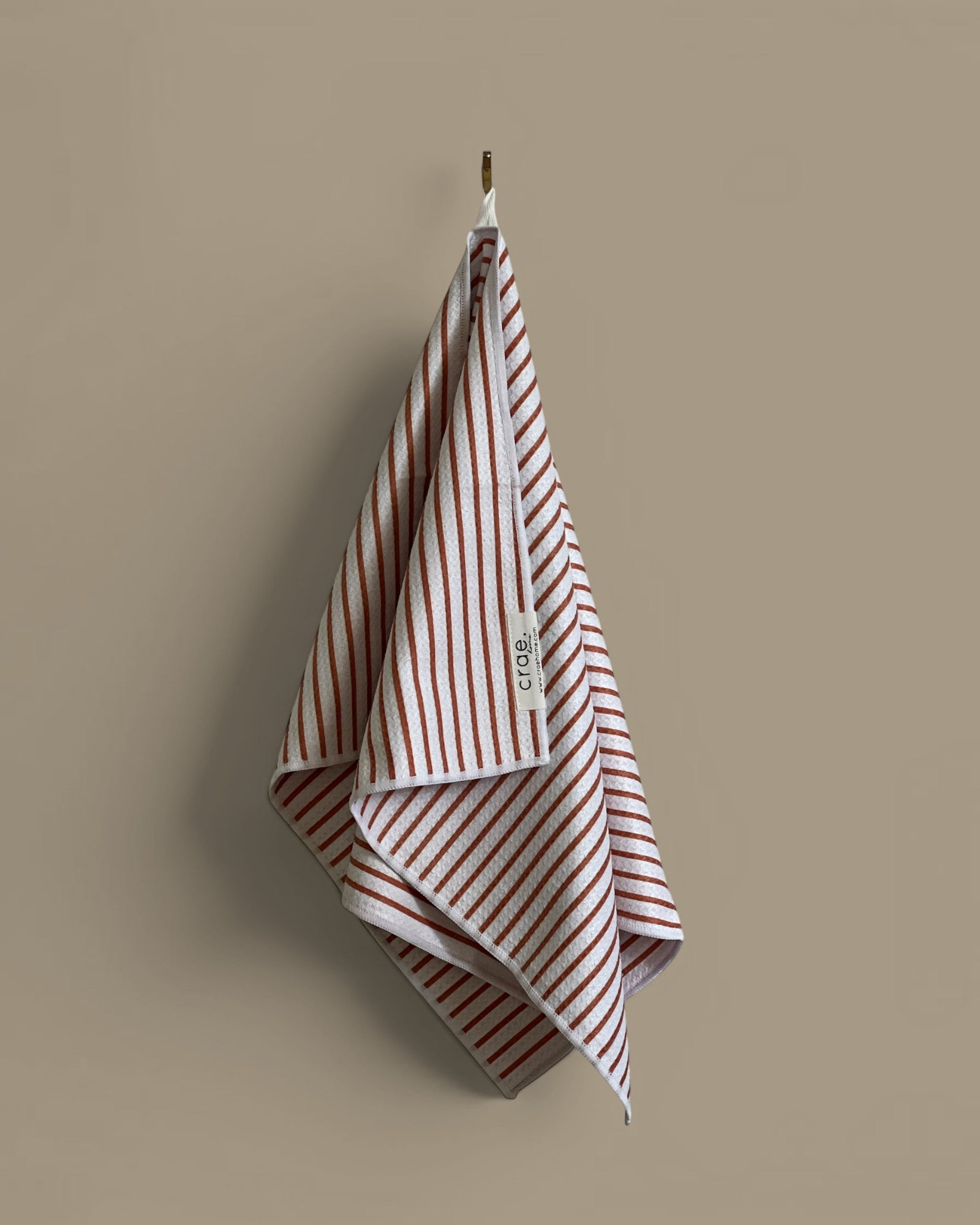 Homestyle Collective white waffle weave hand towel with rust-colored stripes and a textured finish.