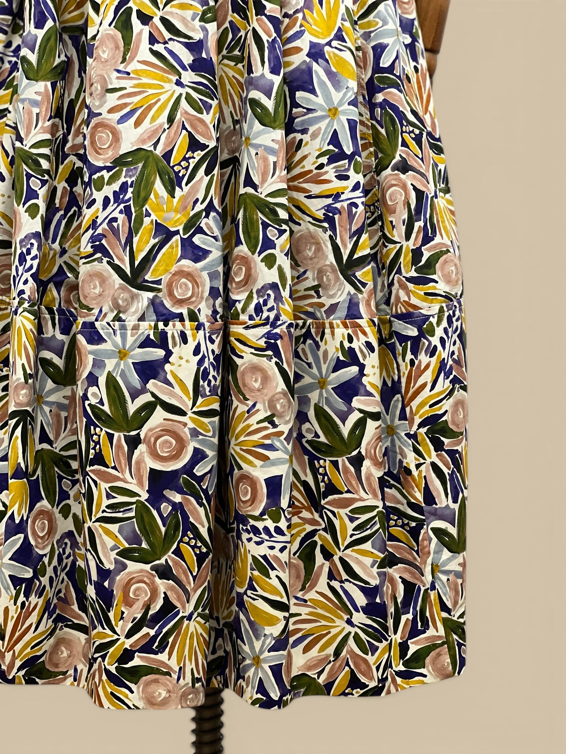 Homestyle Collective watercolor floral A-line midi skirt with a flattering fit and flowing silhouette. Features a vibrant floral print in blue, pink, yellow, and green.