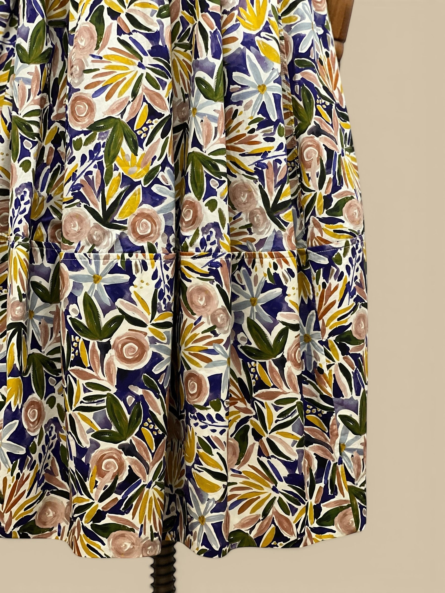 Homestyle Collective watercolor floral A-line midi skirt with a flattering fit and flowing silhouette. Features a vibrant floral print in blue, pink, yellow, and green.