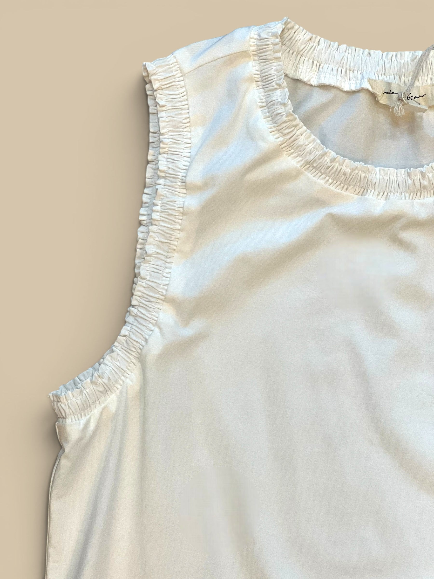 Homestyle Collective white cotton jersey sleeveless top with ruffled neckline and armholes.