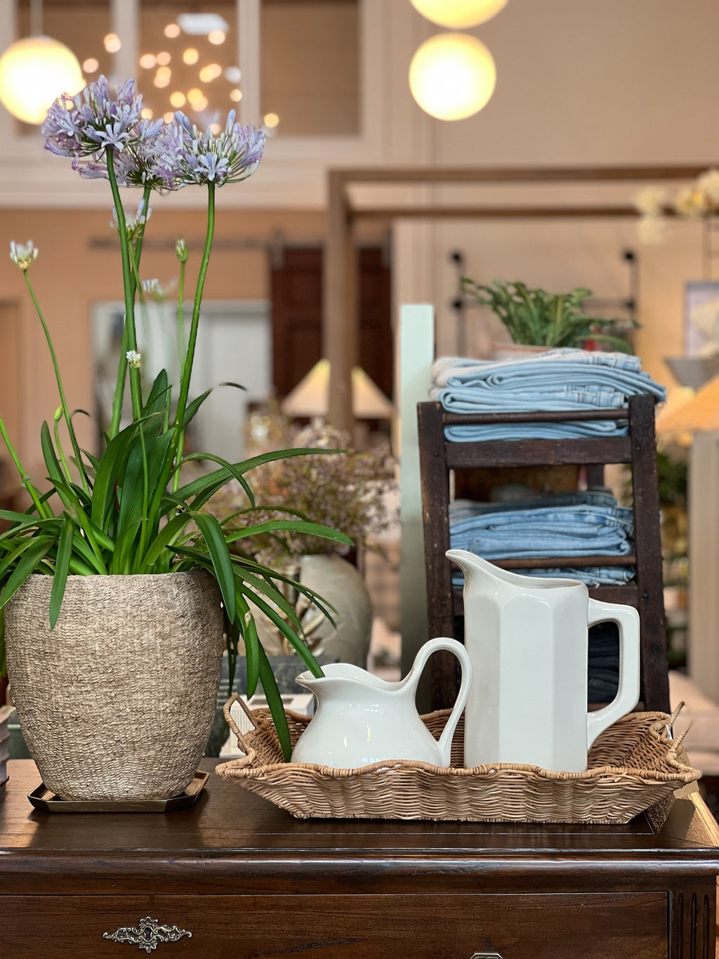 Homestyle Collective white stoneware pitcher with faceted sides and a handle, displayed with a smaller creamer and flowers.
