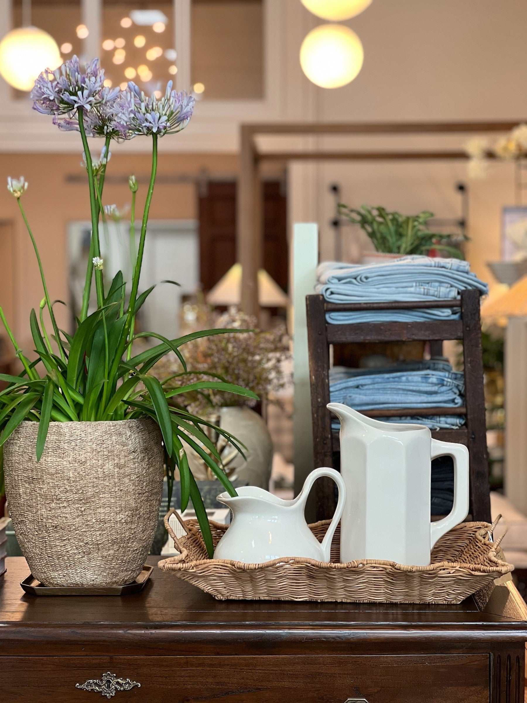 Homestyle Collective white stoneware pitcher with faceted sides and a handle, displayed with a smaller creamer and flowers.