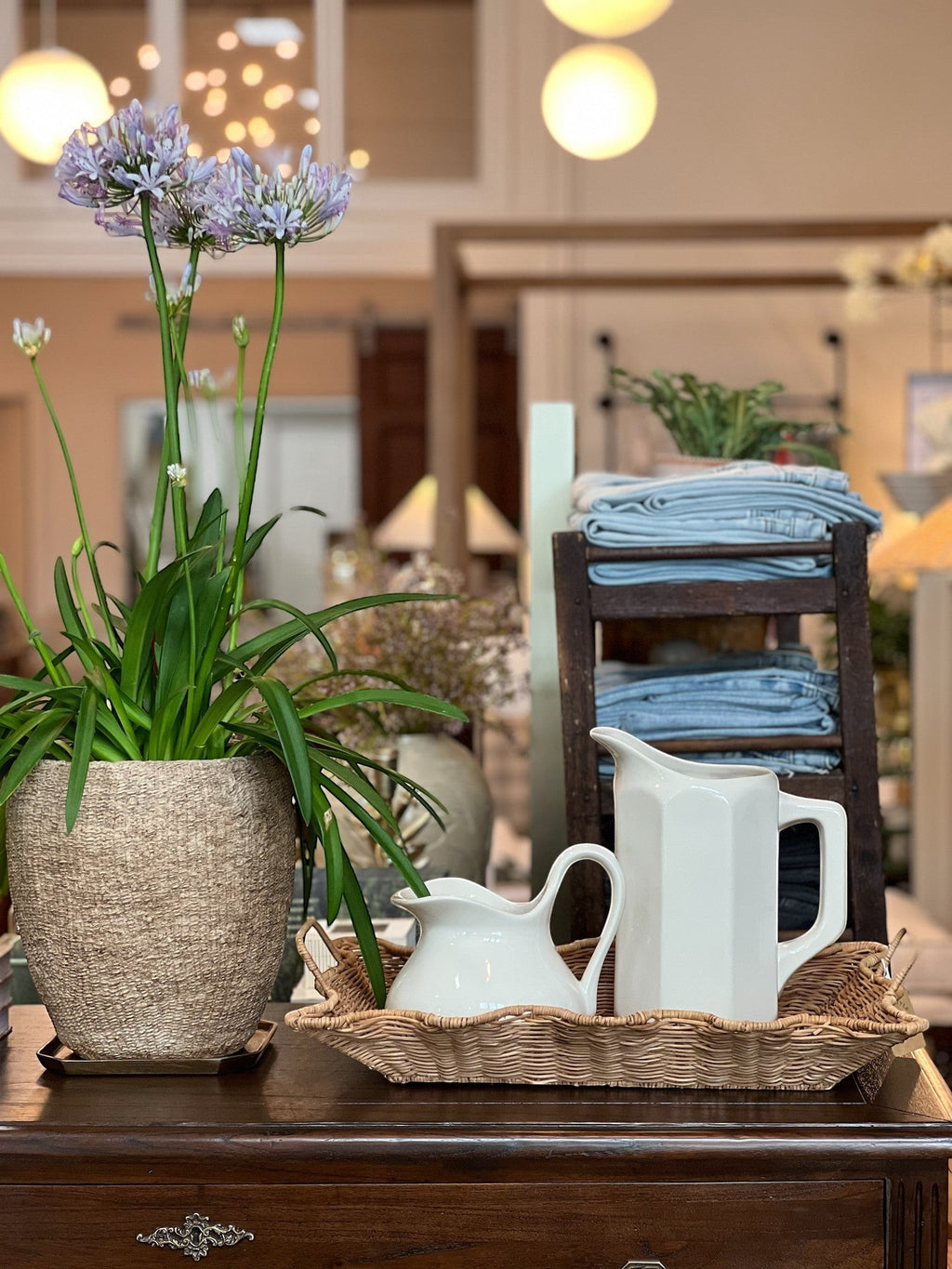 Homestyle Collective white stoneware pitcher with faceted sides and a handle, displayed with a smaller creamer and flowers.