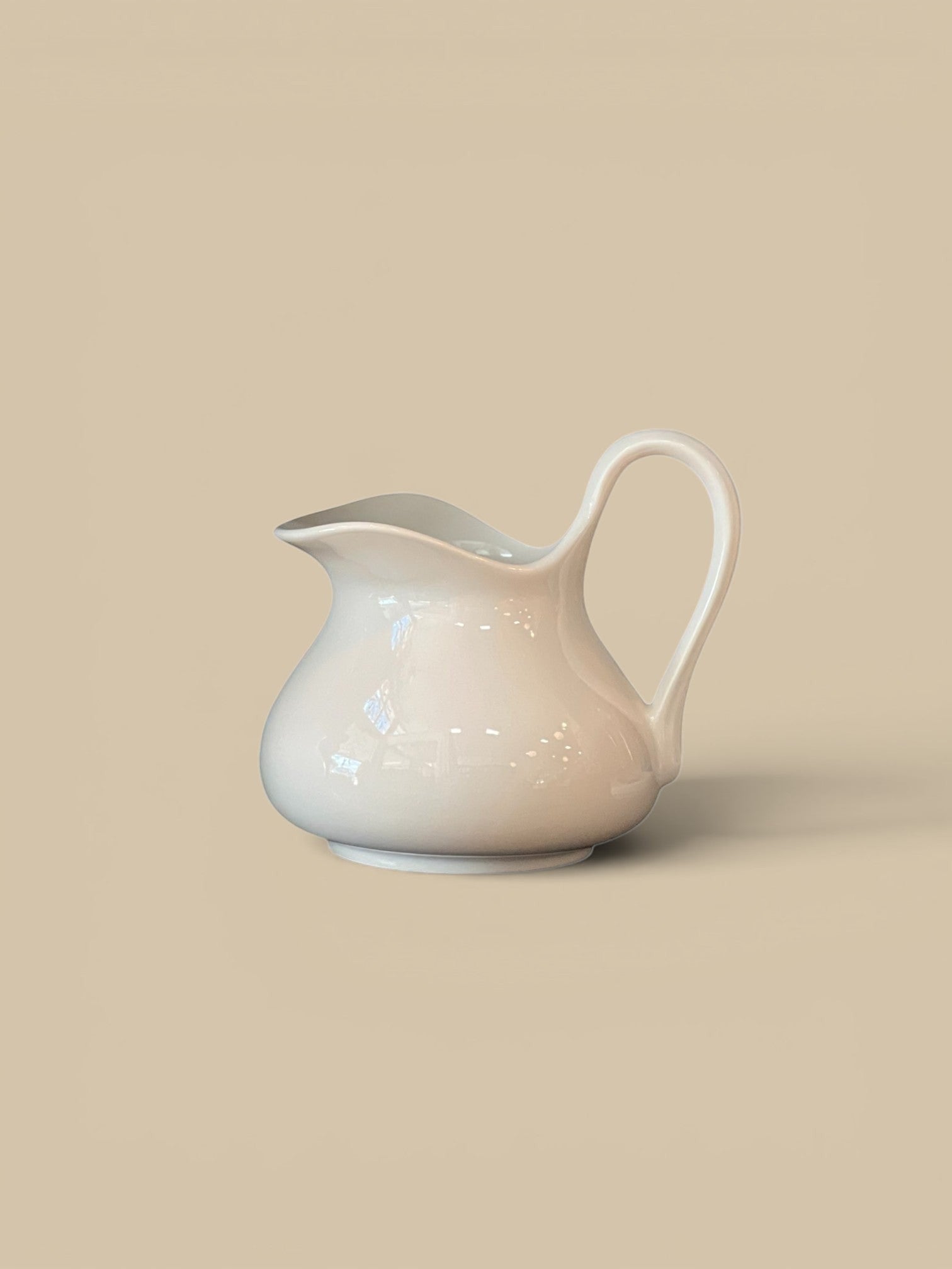 Homestyle Collective flour white stoneware pitcher with a curved handle, perfect for beverages or floral arrangements.