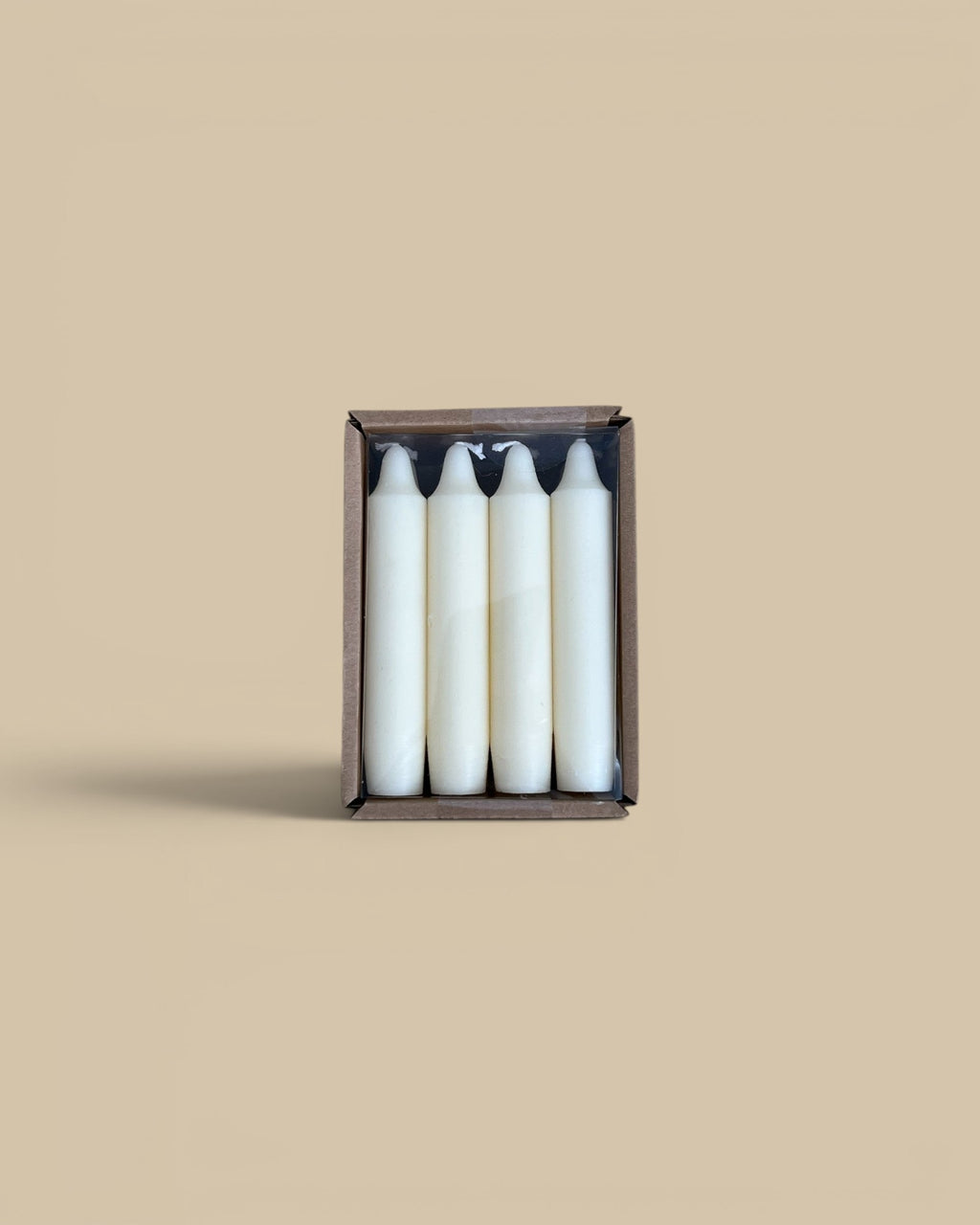 Homestyle Collective set of four unscented white 5-inch taper candles in a brown cardboard box on a rustic surface.