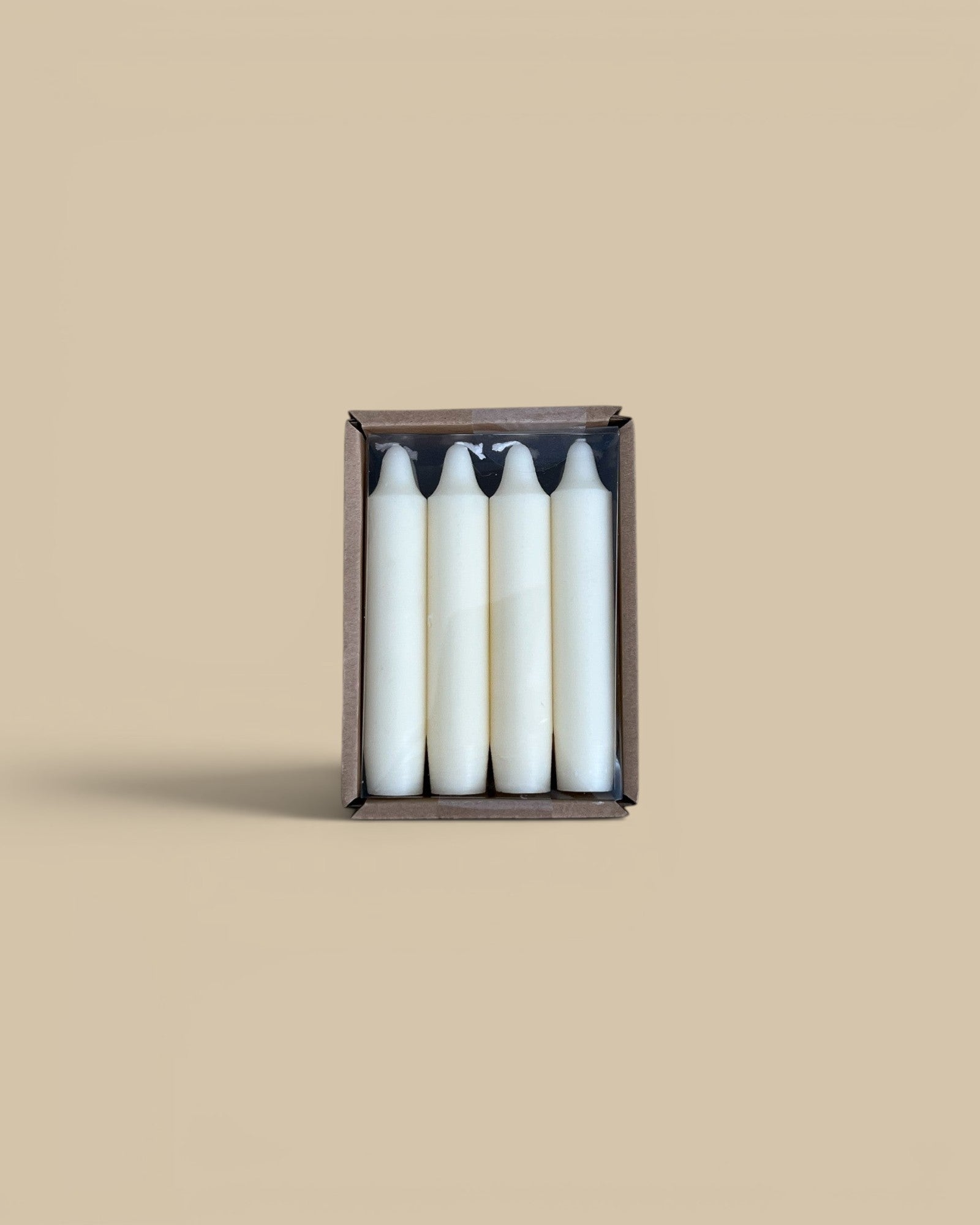 Homestyle Collective set of four unscented white 5-inch taper candles in a brown cardboard box on a rustic surface.