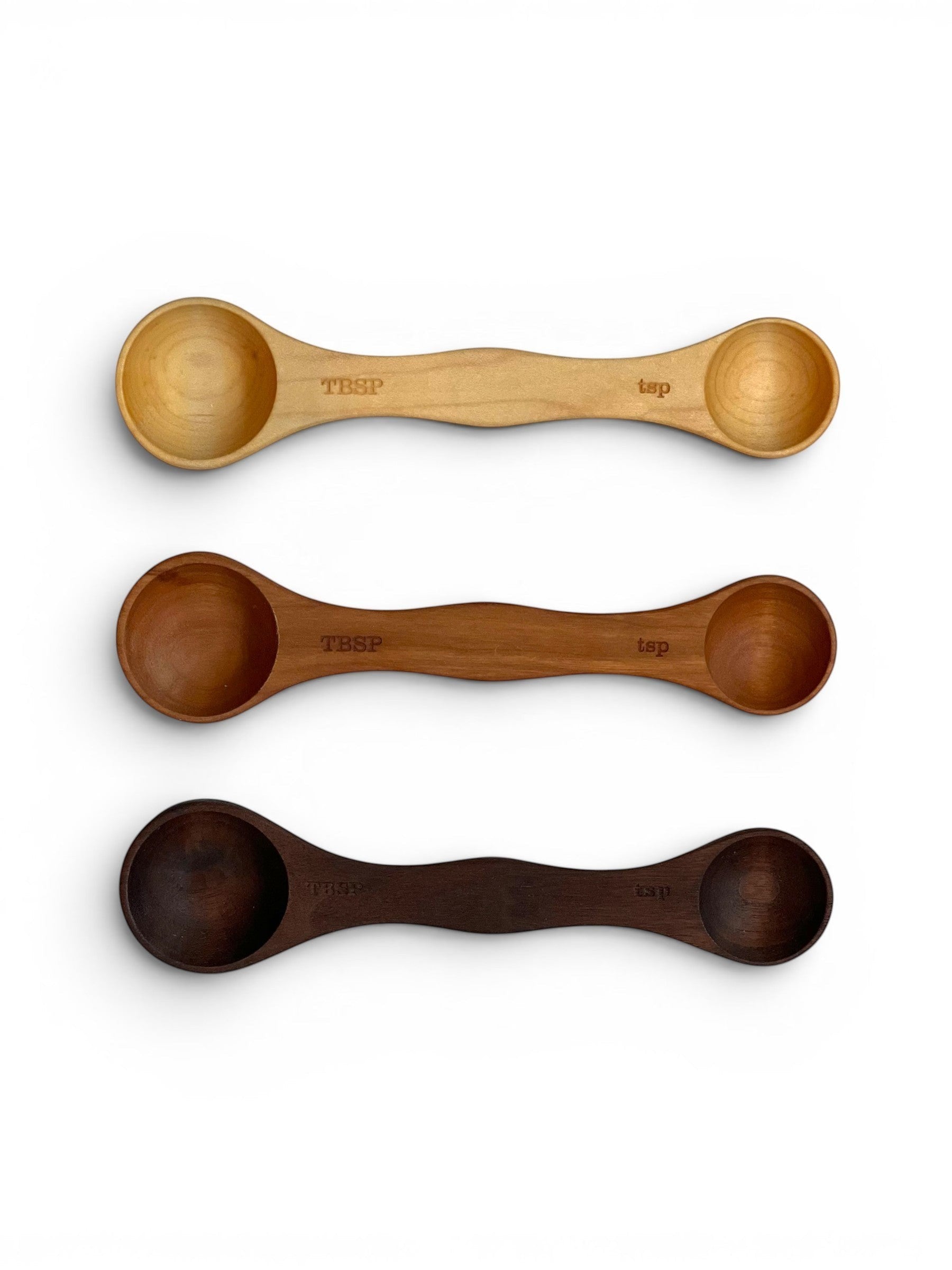 Homestyle Collective wooden measuring spoons in light, medium, and dark wood finishes. Each double-sided spoon has tablespoon and teaspoon ends.